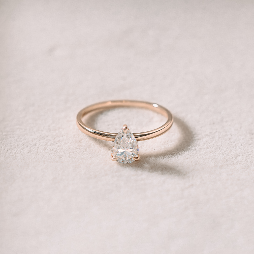 A gold solitaire ring with a pear-shaped stone set in a simple mounting.